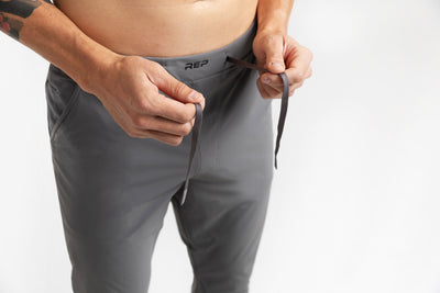 Athlete adjusting the front drawstring on the Cool Gray Men's Felix Pants 2.0 