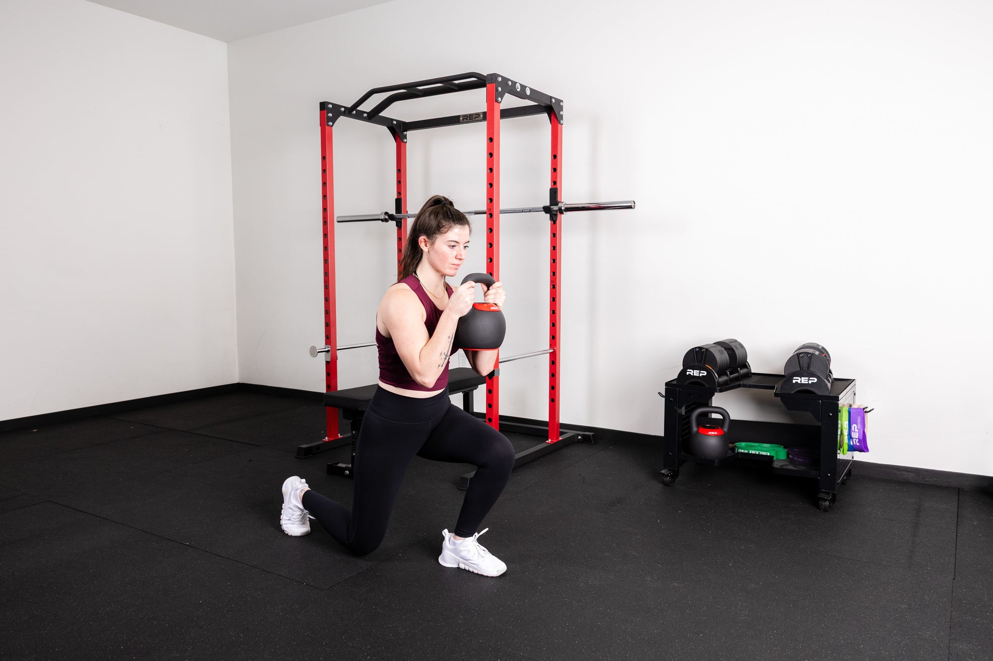 An athlete doing lunges with the REP Adjustable Kettlebells