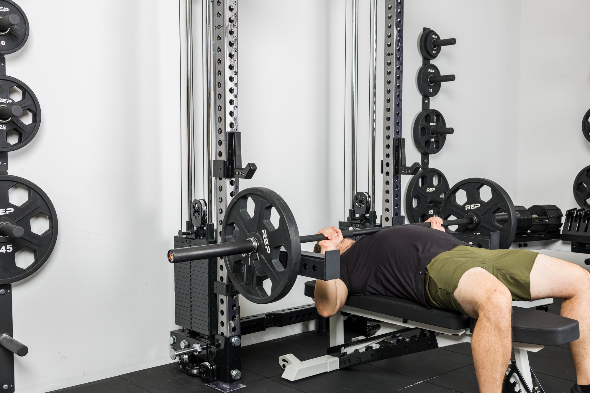 An athlete bench pressing off the front of the Wall-Mounted Athena