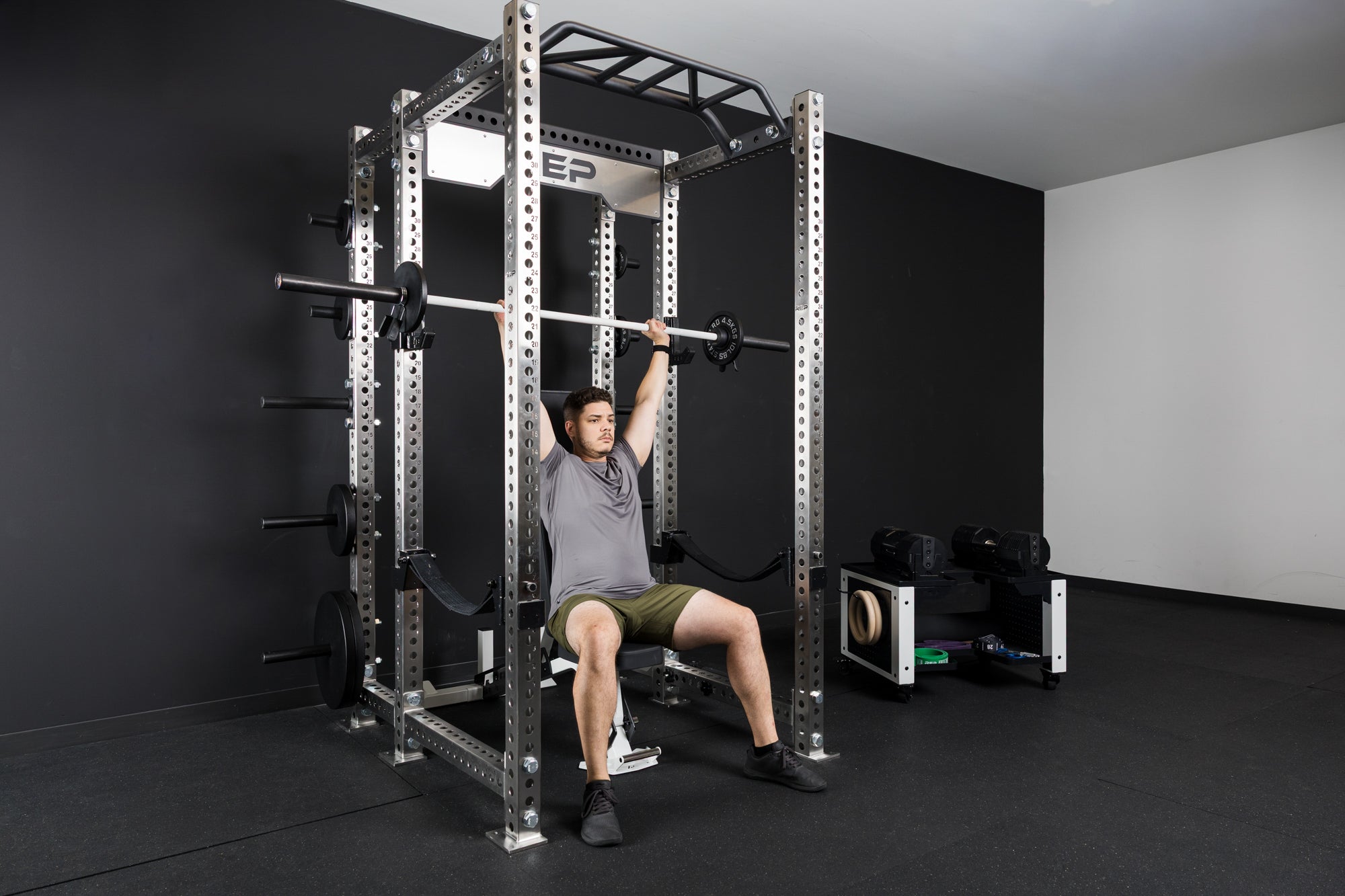 An athlete doing barbell shoulder presses with the Colorado barbell and old school iron weight plates
