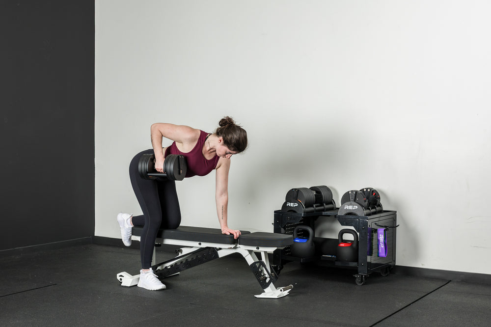 An athlete doing dumbbell rows on a Nighthawk bench with the Quickdraw adjustable dumbbells