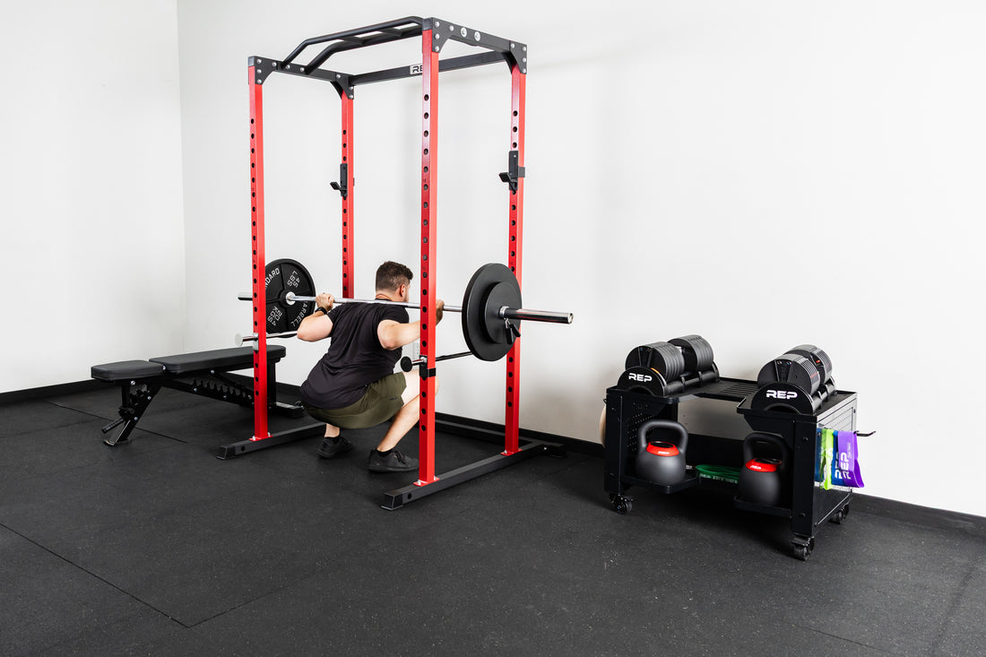 An athlete doing squats with the Delta basic barbell and old school iron plates in the PR-1100 rack
