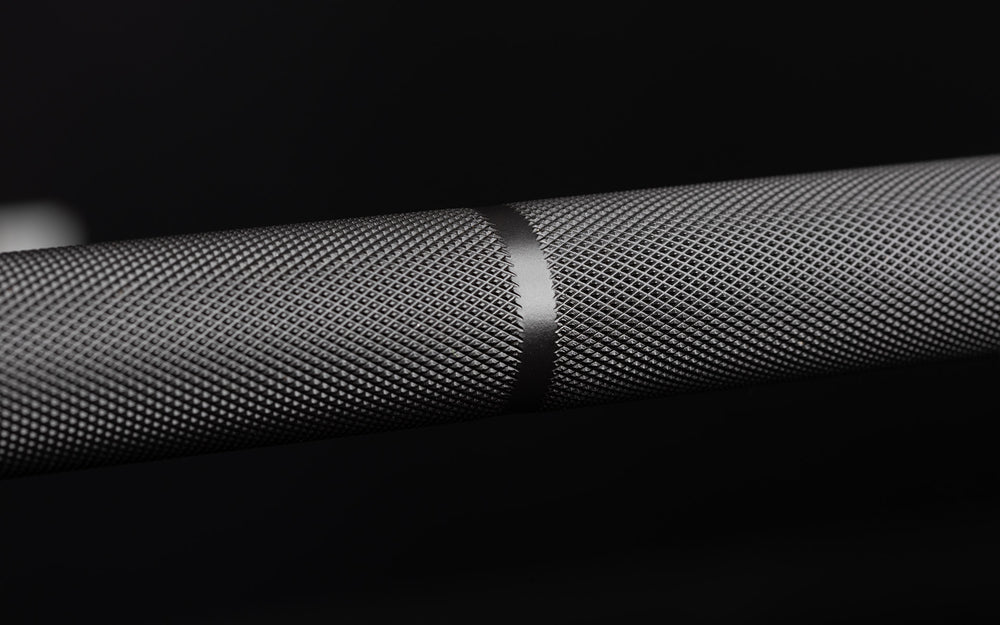 Close-up view of the volcano knurled shaft and a powerlifting knurl marking on the REP Hades Deadlift Bar.