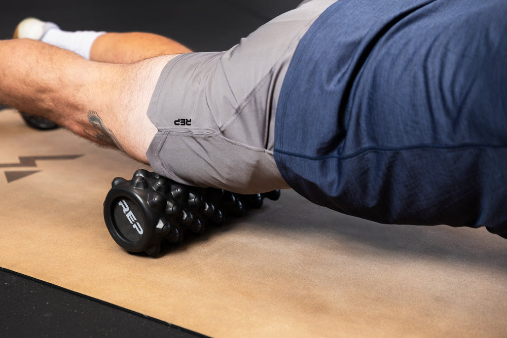 Person using High Density Foam Roller to roll out quads on cork yoga mat.