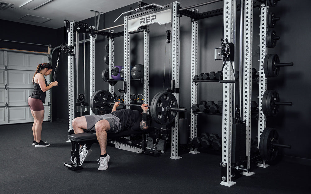 2 athletes training on the Hyperion series 1. 1 using left side cable while other benches in the center.