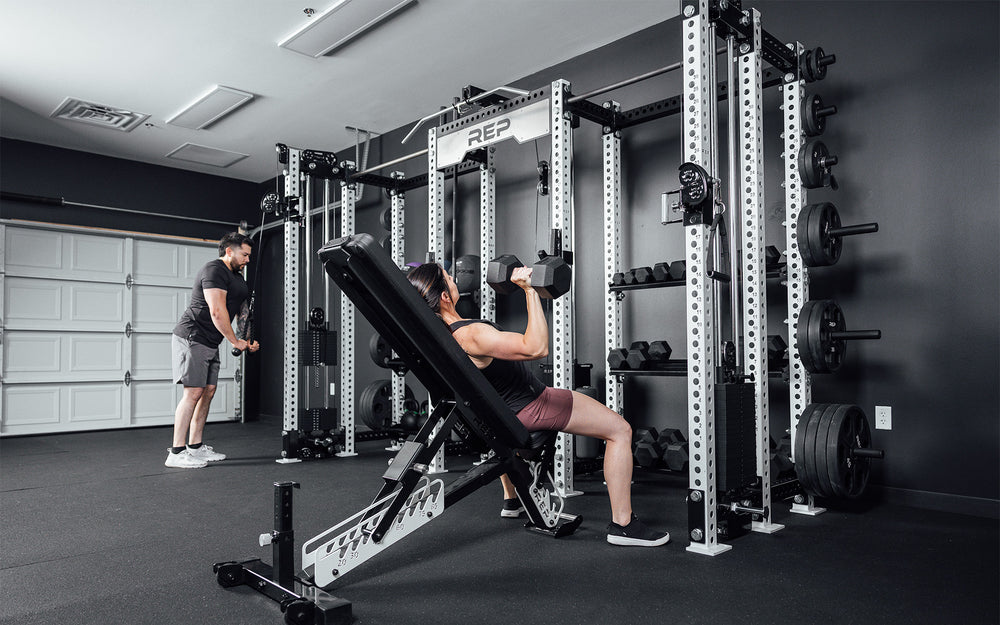 2 athletes training on the Hyperion series 1. One using cables on the left while the other uses dumbbells on the right.