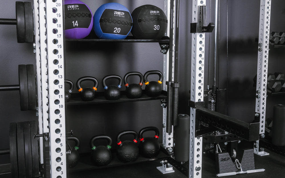 Close-up shot of the left side of the Hyperion series 1 with spotter arms, hanging barbells, med ball and kettlebell storage, and weight horns.