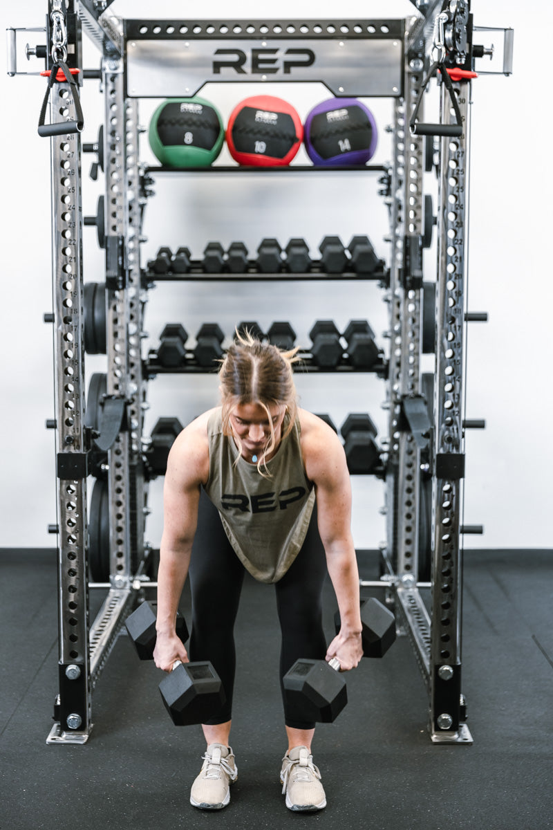 Someone using hex dumbbells in front of rack and dumbbell shelves on in-rack storage