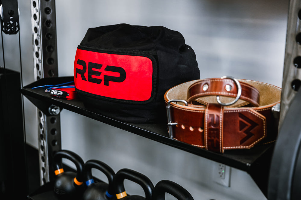 Off-Rack Storage - close up of flat storage shelf holding a weight belt, wrist straps, jump ropes, and a stone sandbag