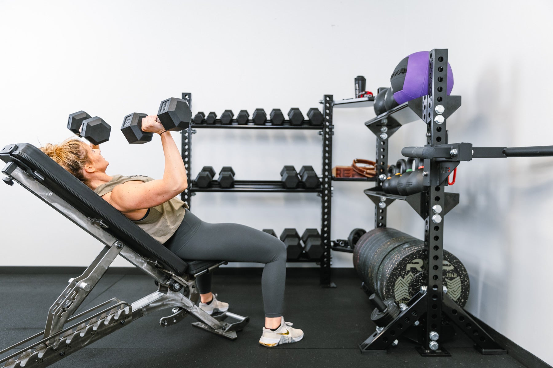 omeone using hex dumbbells in front of Corner Shelf Stand-Alone Storage System and dumbbell shelves