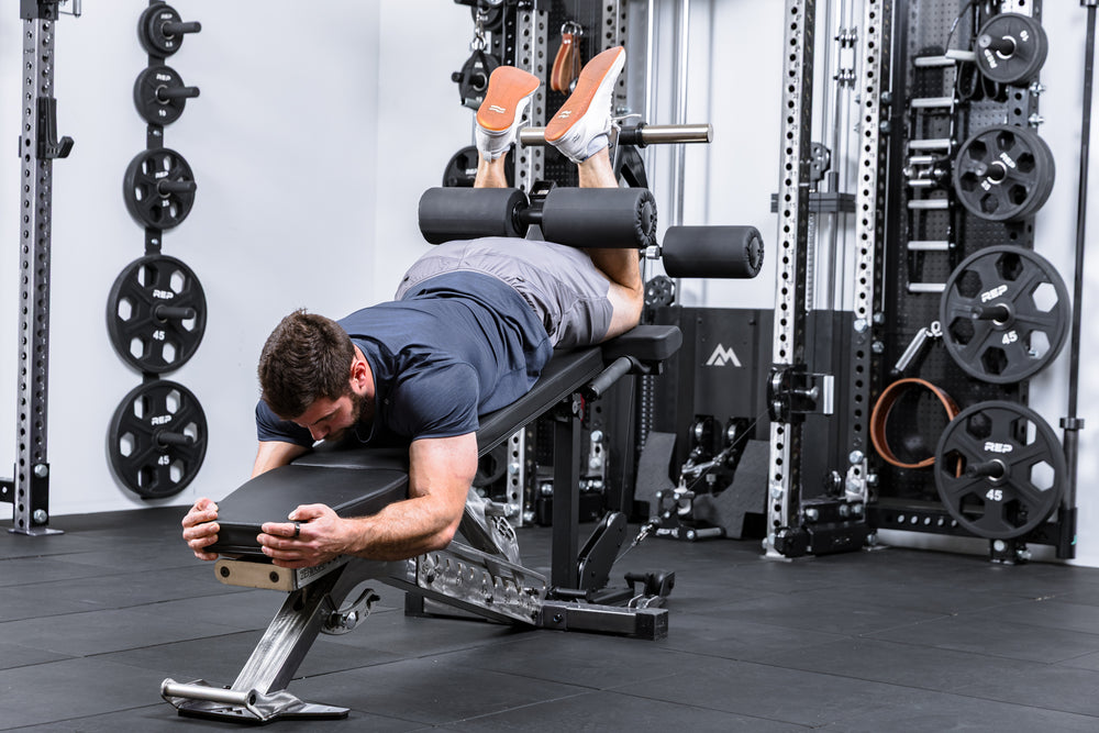 Athlete using cable resistance to do hamstring curls on theLeg Extension & Leg Curl Bench Attachment