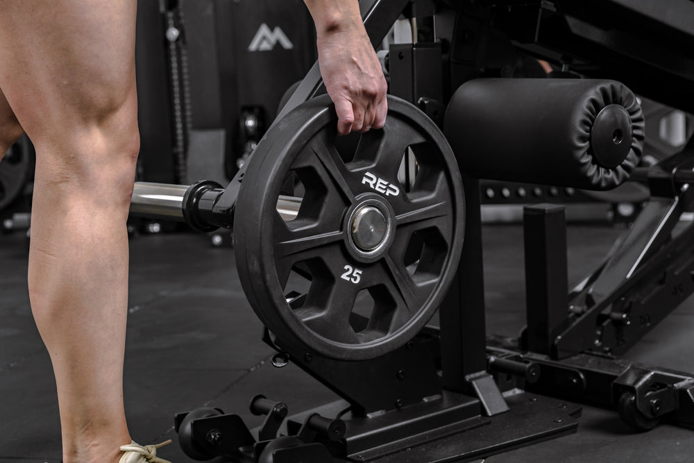 Athlete loading a weight plate onto the Leg Extension & Leg Curl Bench Attachment
