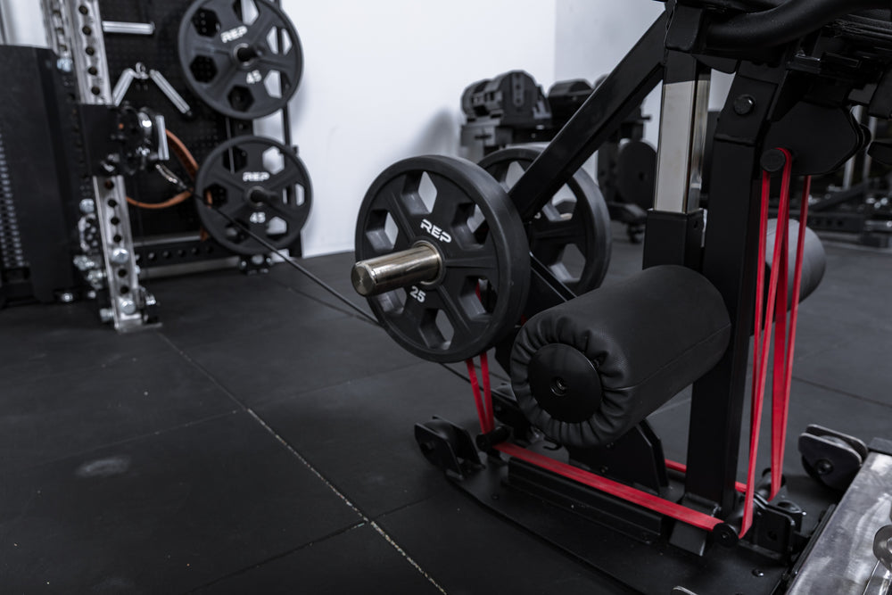 Close-up shot of weight plates, resistance bands, and cable resistance loaded onto the Leg Extension & Leg Curl Bench Attachment