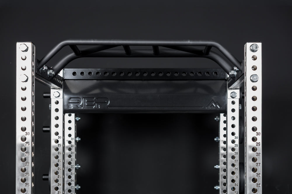 Close up of the stamped Logo Plate Crossmember 2.0 on a REP power rack in front of a black background