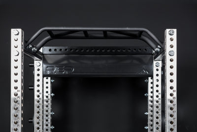 Close up of the stamped Logo Plate Crossmember 2.0 on a REP power rack in front of a black background
