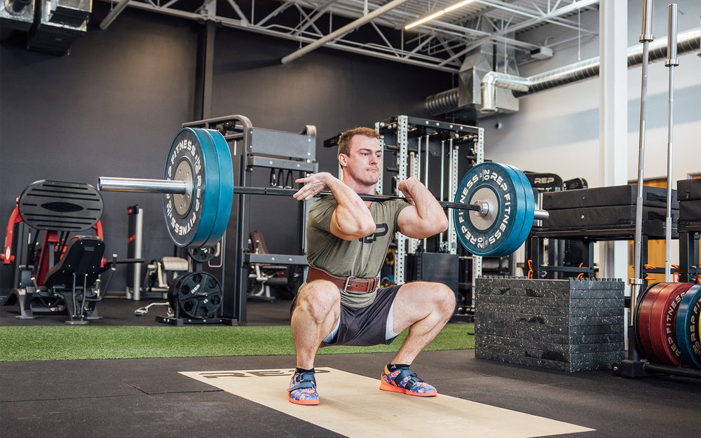 Athlete in the bottom catch position of a clean and jerk while wearing a brown REP Leather Olympic Lifting Belt.