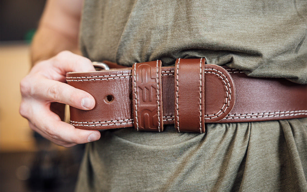 Close-up front view of athlete putting on the brown REP Leather Olympic Lifting Belt.