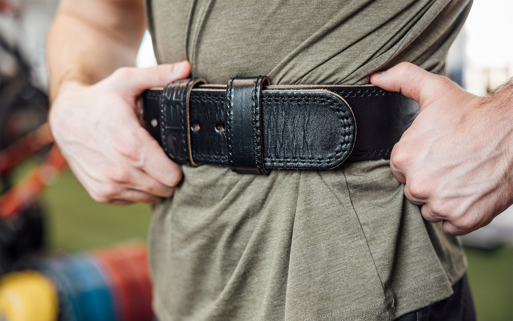 Close-up front view of athlete putting on the black REP Leather Olympic Lifting Belt.