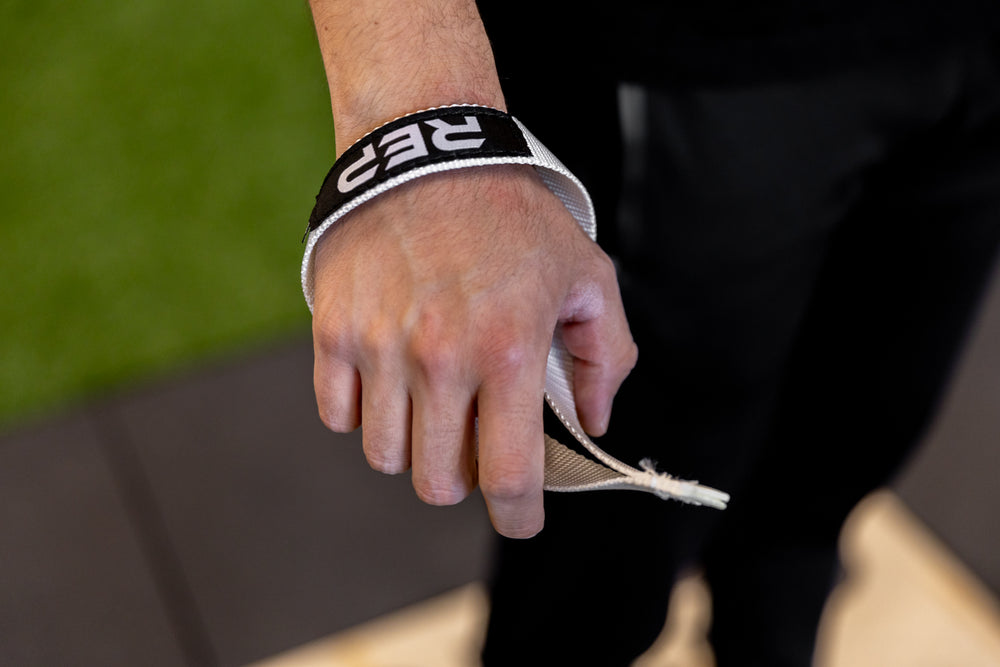 Close-up view of the right-sided white REP Olympic Lifting Strap on an athlete's wrist.