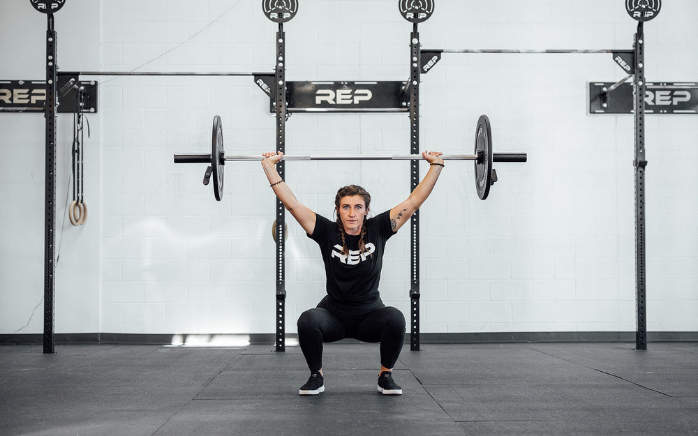 Female lifter in the bottom catch position of a snatch using a loaded REP Mesa Technique Bar.