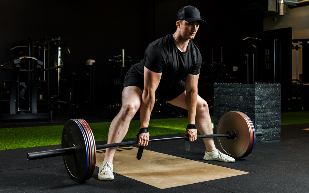 An athlete deadlifting with Rep Fitness Calibrated Steel Plates (LB) loaded on the barbell