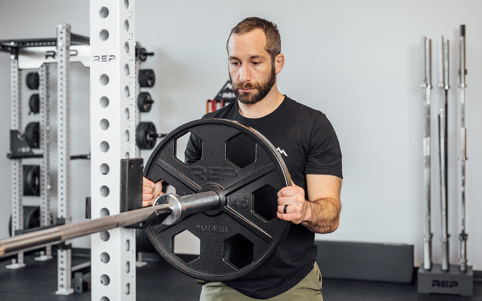 Lifter loading a 45lb USA-Made Equalizer Iron Plate onto a racked barbell.