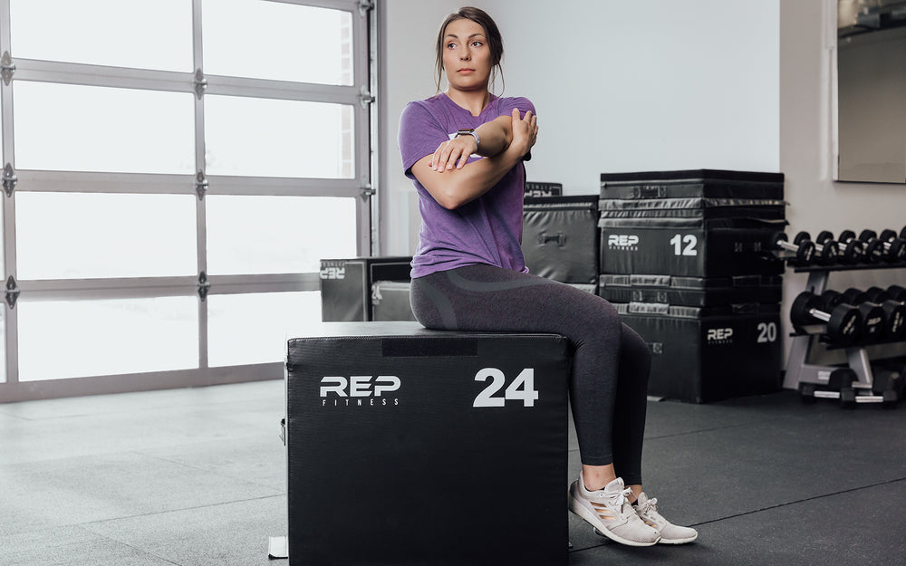 Female athlete stretching on a 24" REP Stackable Soft Plyo Box.