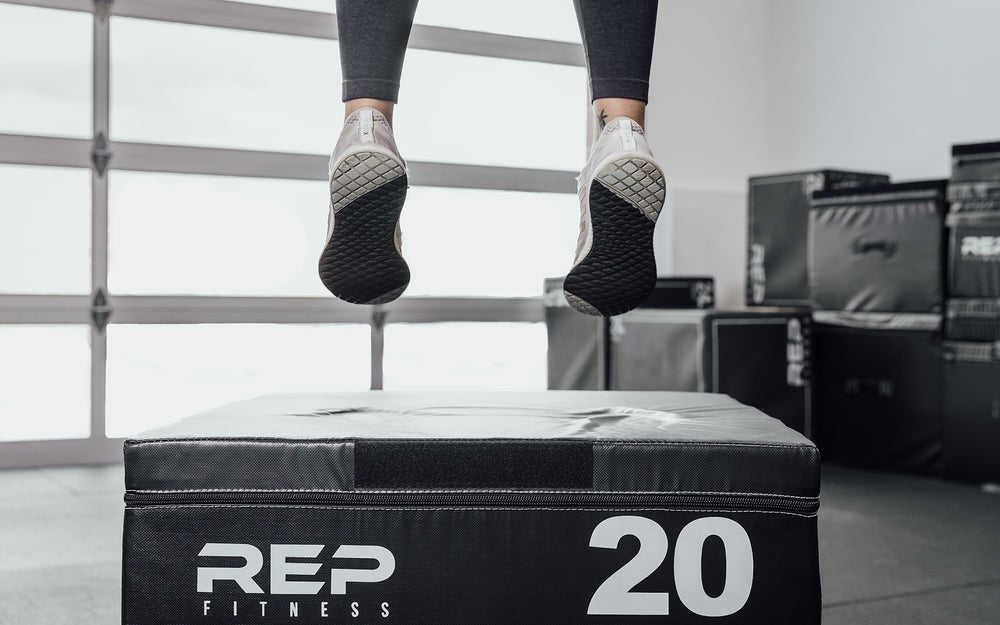 Female athlete performing box jumps on a 20" REP Stackable Soft Plyo Box.