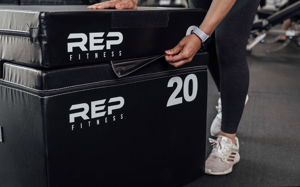 Female athlete securing the 6" REP Stackable Soft Plyo Box to the 20' via the 10" Velcro strap.