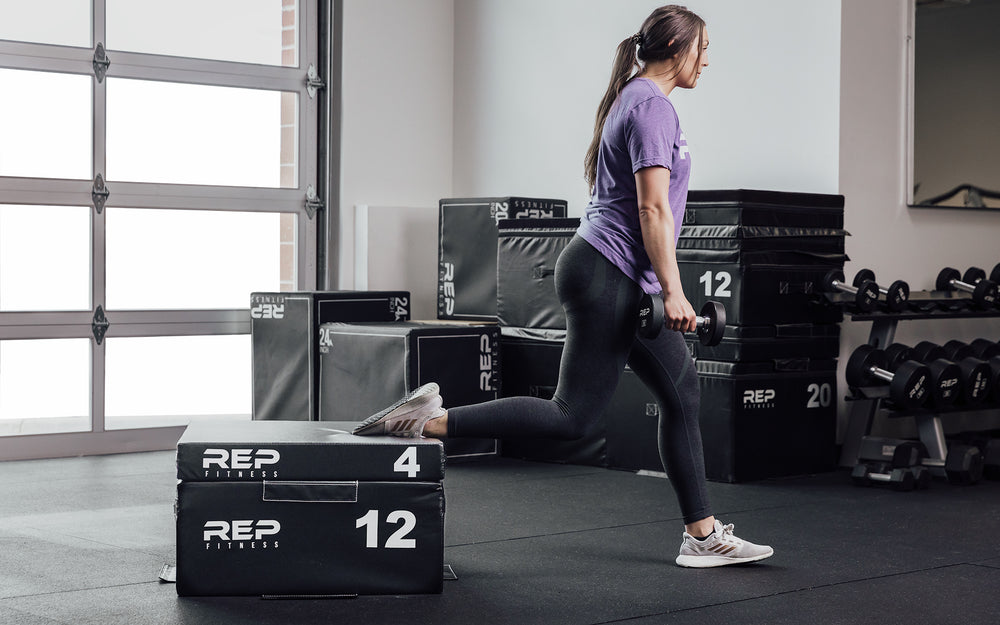 Female athlete performing a split squat with her back foot elevated on a 12" and 4" REP Stackable Soft Plyo Box.