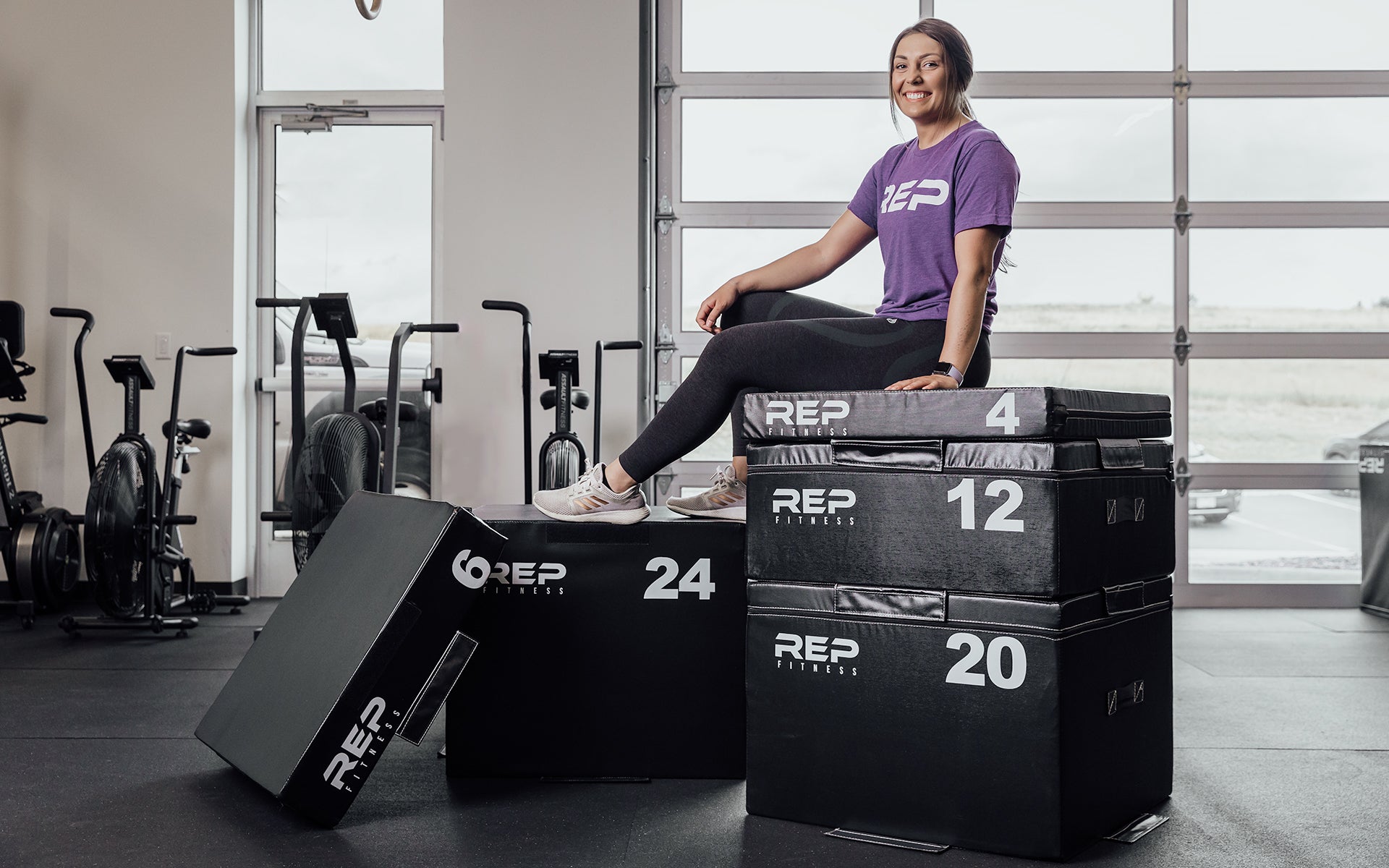 Female athlete sitting on top of a full set of REP Stackable Soft Plyo Boxes.