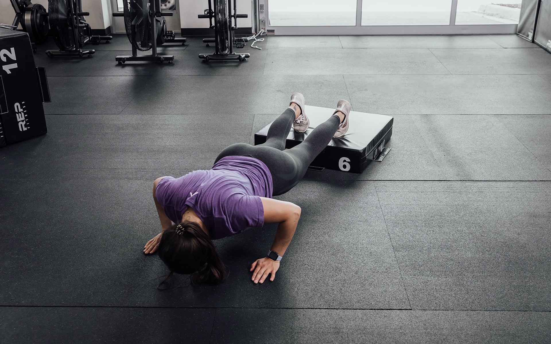 Female athlete performing deficit push-ups with her feet elevated on a 6