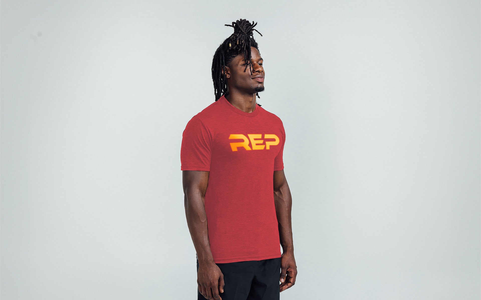 Model wearing the REP Fitness Men's Daily Driver 2.0 Tri-Blend Crew T-Shirt in Heather Red with a Gold graphic