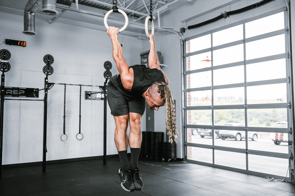 Athlete working out on REP Competition Gymnastic Straps and Wood Rings hanging from metal ceiling infrastructure