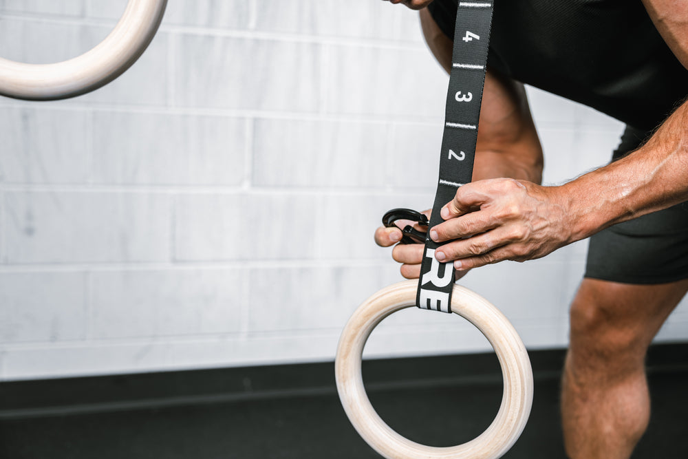 Athlete attaching a Wood Ring to the REP Competition Gymnastic Straps