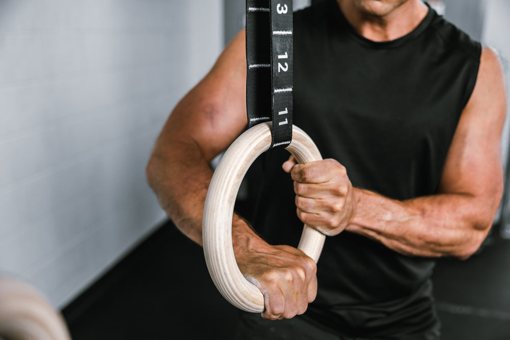 Athlete applying body weight to the REP Competition Gymnastic Straps and Wood Rings to check setup