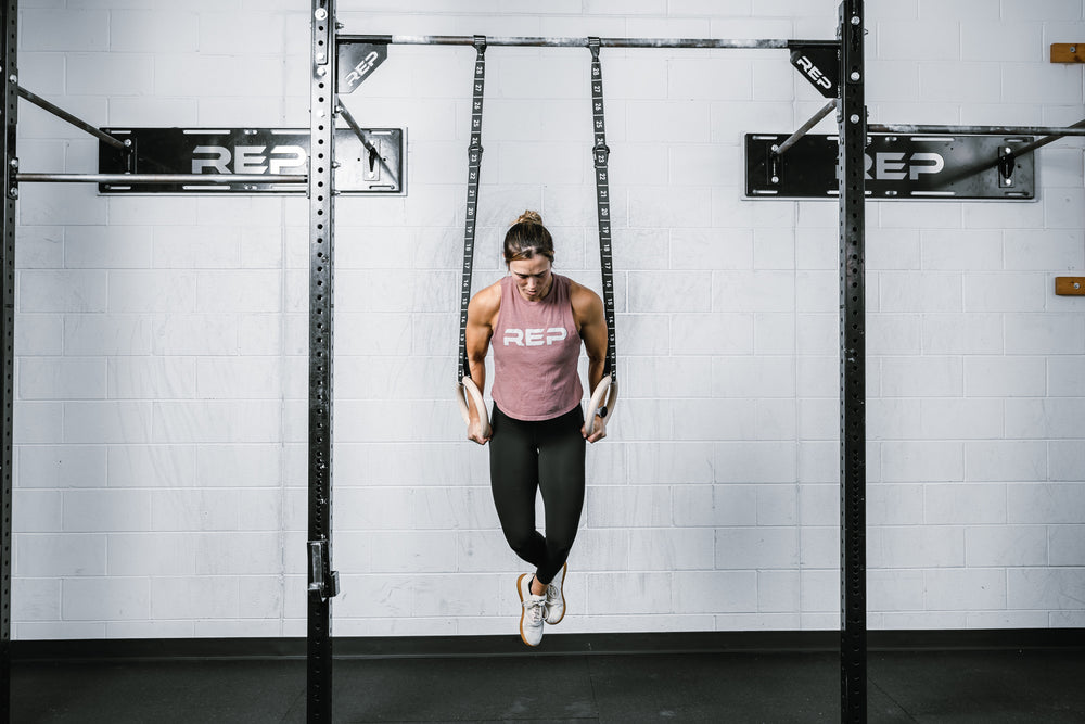 Athlete holding themselves vertically on the REP Competition Gymnastic Straps to the Wood Rings on a REP Wall-mounted Rig
