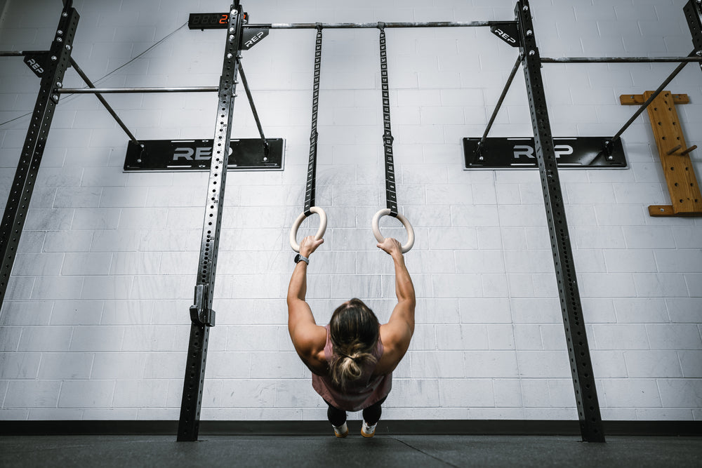 Athlete lowering themselves parallel to the ground with REP Competition Gymnastic Straps and Wood Rings