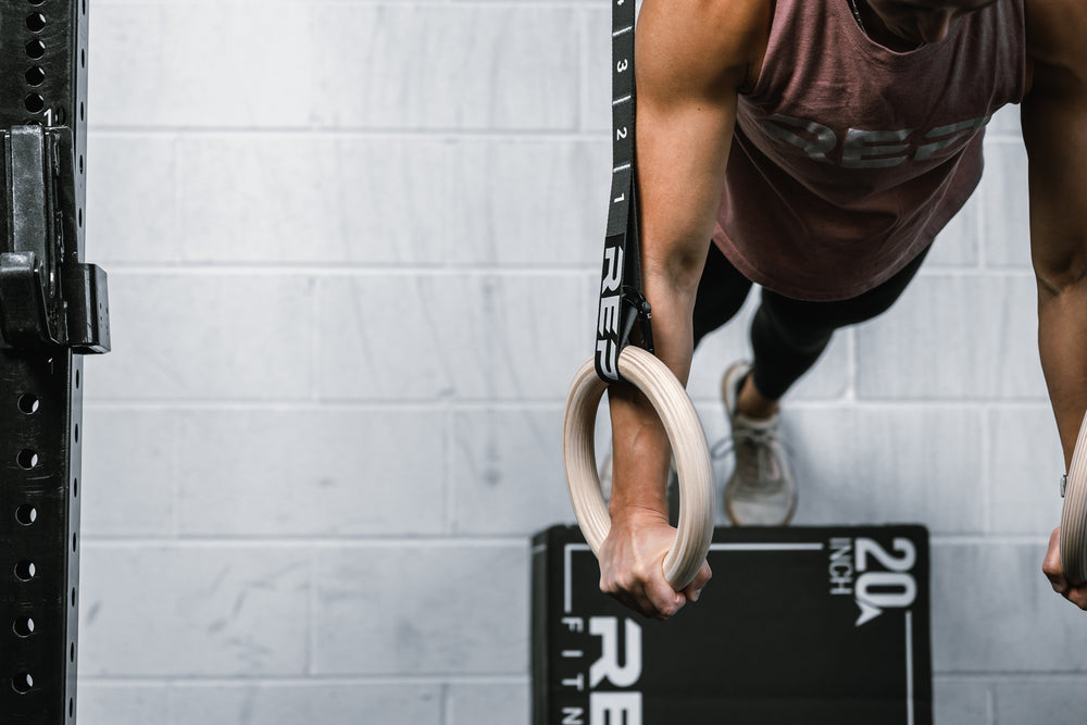 Close-up shot of an athlete doing pushups on REP Competition Gymnastic Straps and Wood Rings from a Soft Plyo box