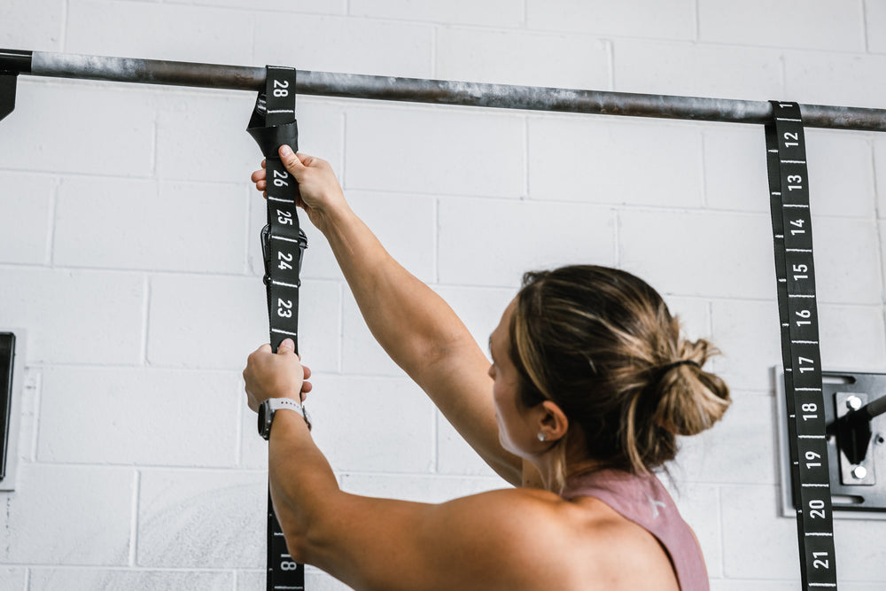 Athlete securing the REP Competition Gymnastic Straps to a REP Wall-mounted Rig