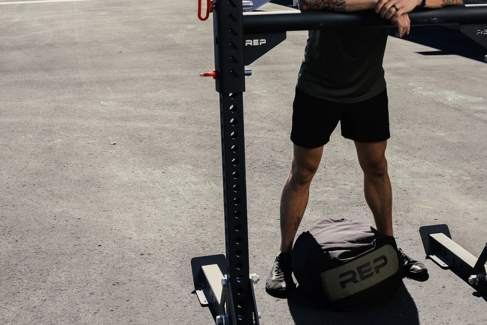 Person using a Rep Fitness yoke to do stone sandbag toss overs 