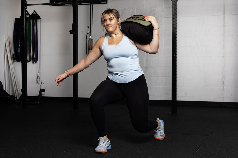Person exercising with a stone sandbag in a gym setting