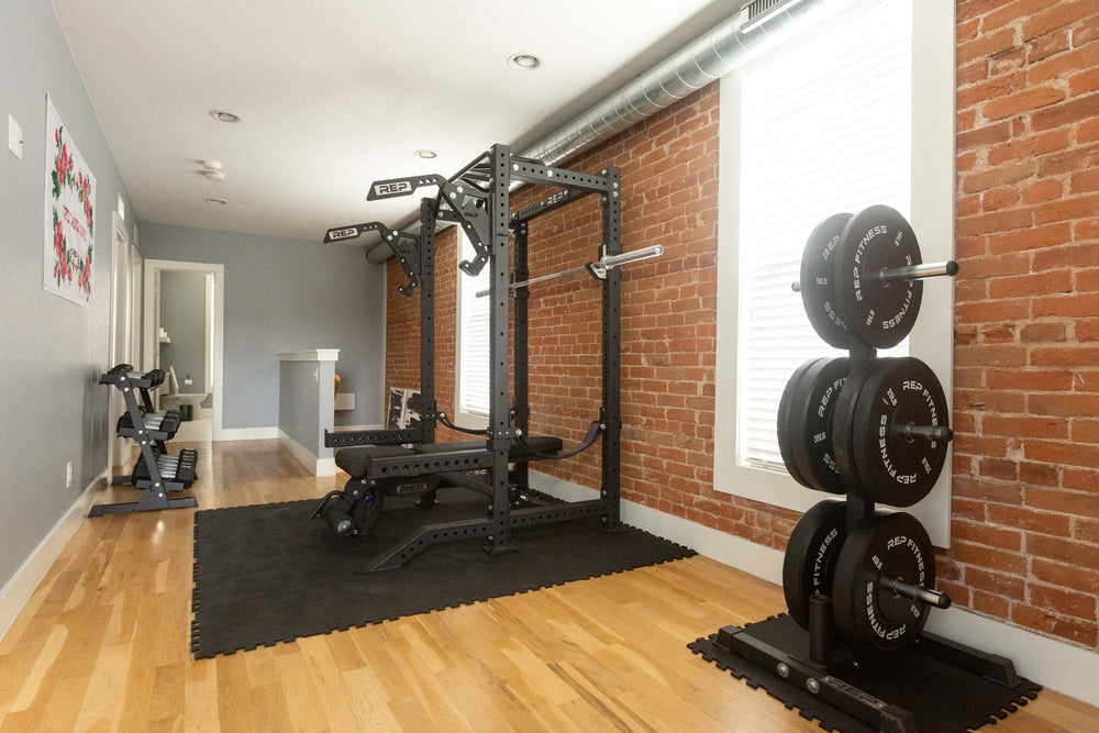 Rack, bench, and weight plate tree on top of Rubber Floor Tiles on a wood floor