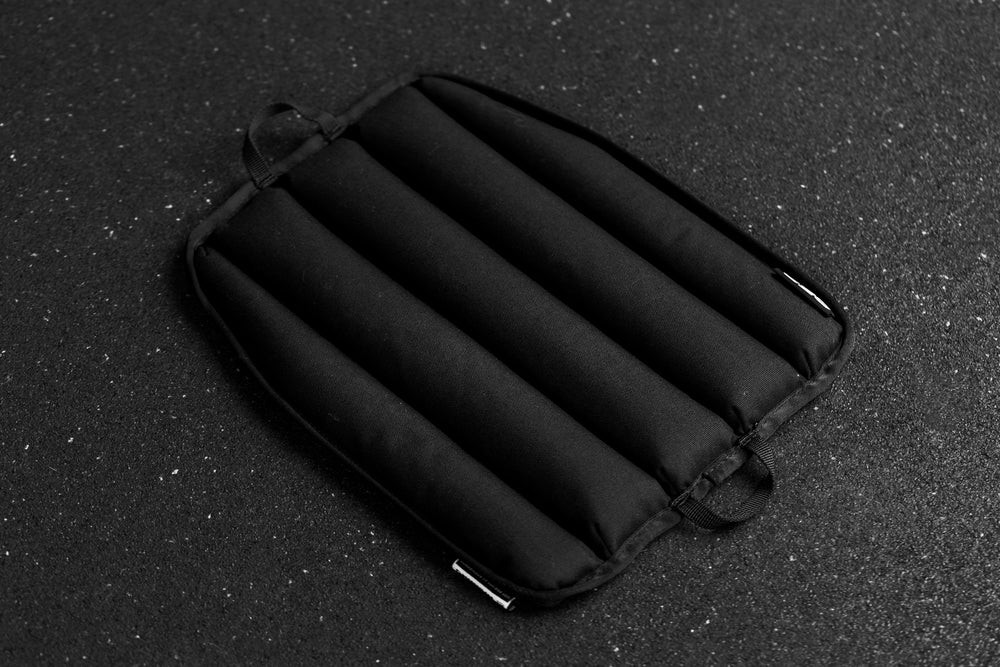 Black soft weight vest plate with ribbed texture on a dark textured background