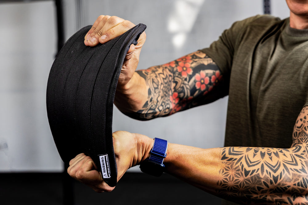Person holding and bending a soft weight vest plate to show its flexibility