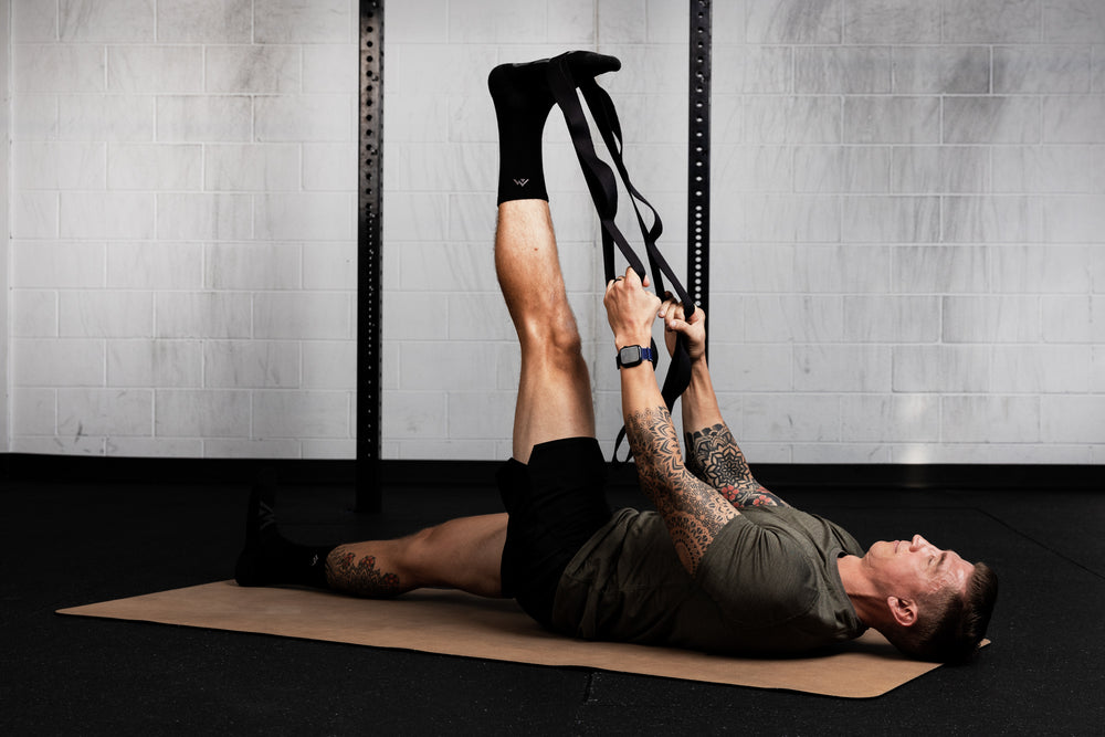 Person exercising using stretching band on a mat in a gym setting