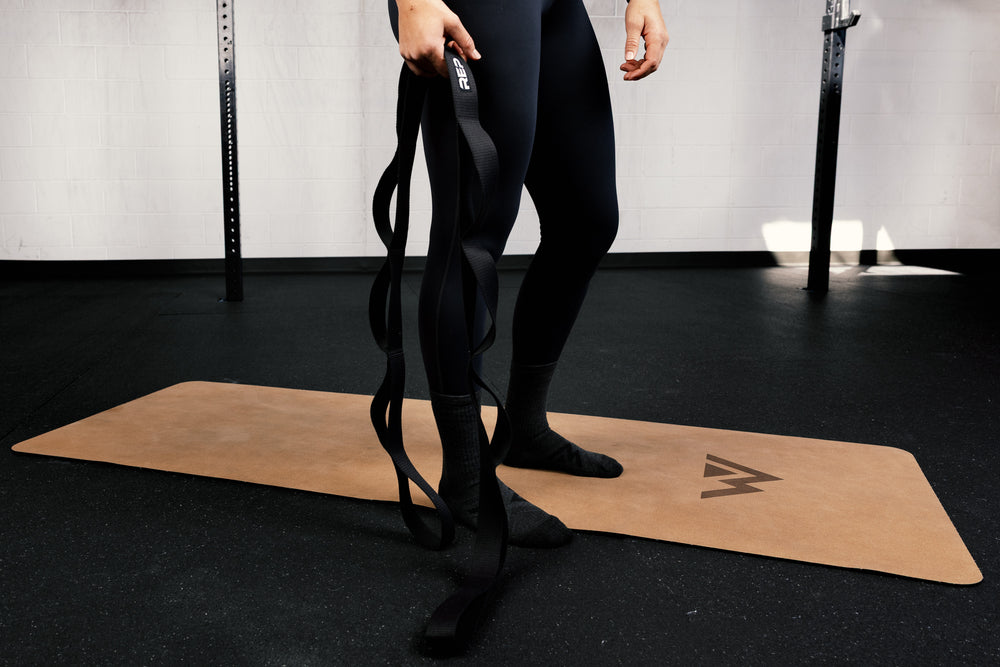 Person holding stretching strap on a mat in a gym setting