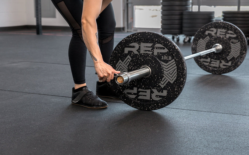 Athlete placing a spring clip on a loaded REP 15kg Teton Training Bar.