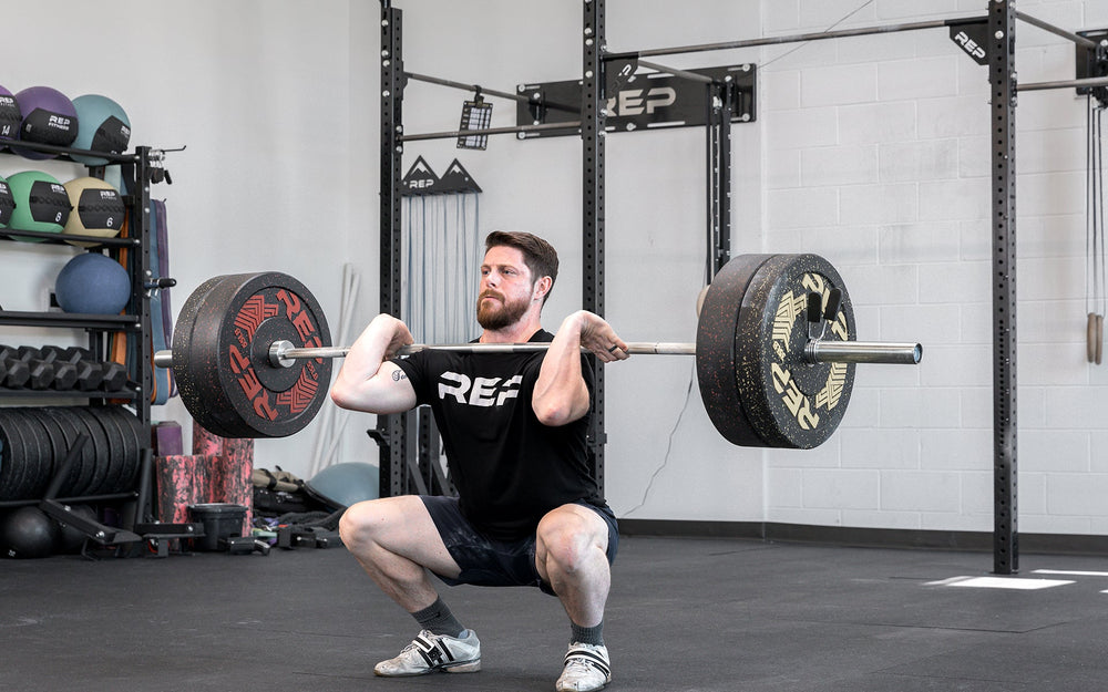 Male lifter in the bottom catch position of a clean and jerk using a loaded REP Teton Training Bar - 20kg.