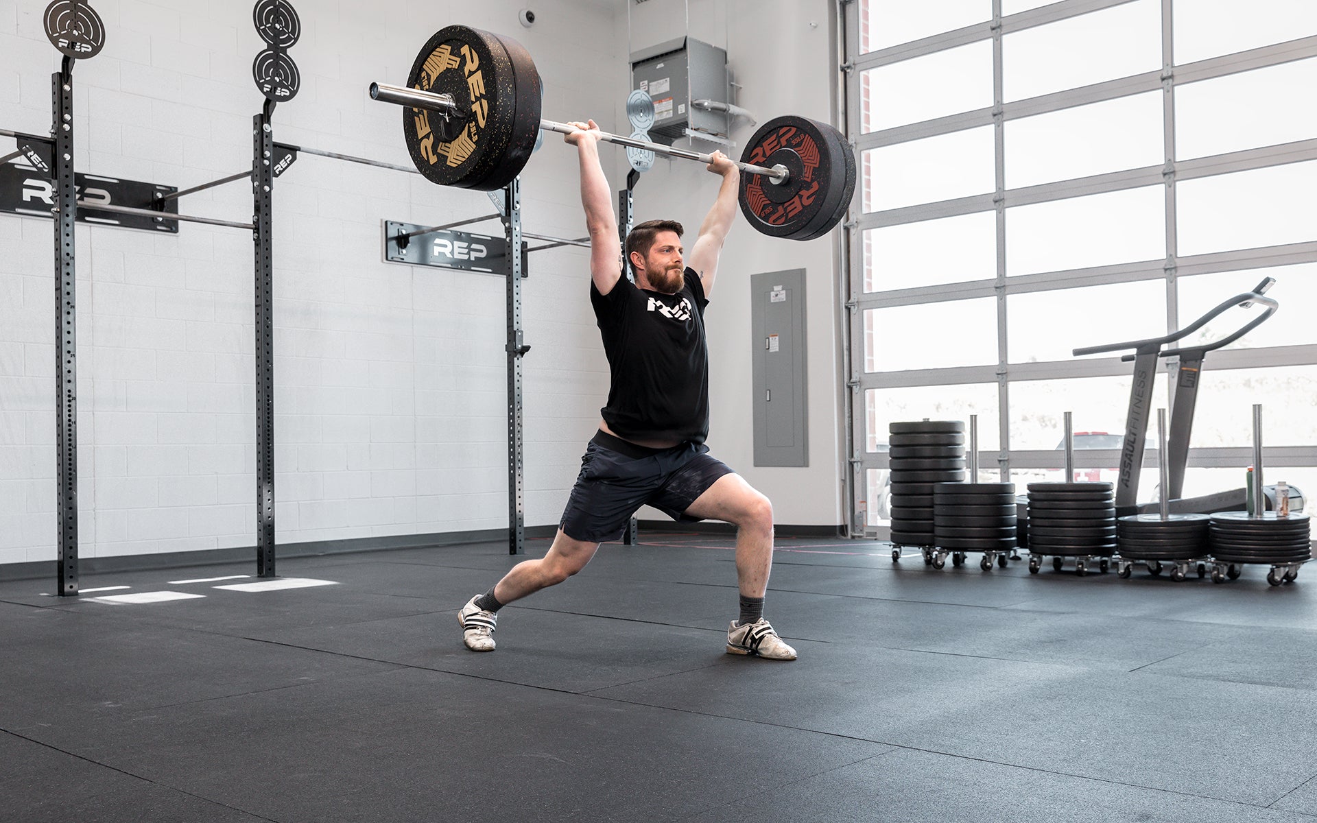 Male lifter in the catch position of a split jerk using a loaded REP Teton Training Bar - 20kg.
